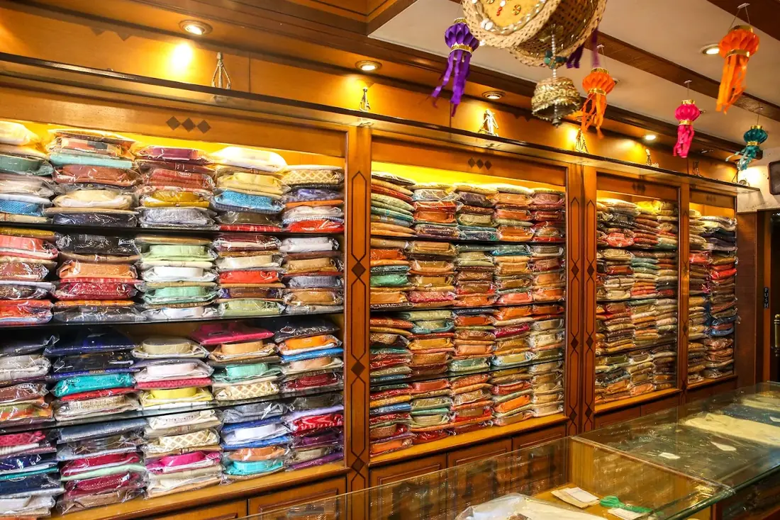 Wall of shelves stacked with packed kurta sets in many colours